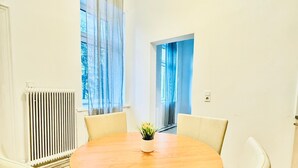 A round table with four chairs in a room with white walls and a radiator. - Modern 3BR Apartment 10 Min to FAC Platz (Wien)