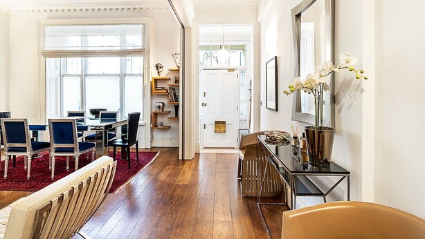 Un salón espacioso con comedor, suelo de madera y un ventanal grande.