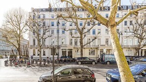Una calle con coches estacionados, bicicletas y un edificio con varias ventanas y balcones.