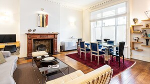 Una sala de estar con chimenea, un comedor con sillas azules, un televisor y una estantería.