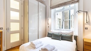 Un dormitorio con cama, ventana con vistas, armario y mesita de noche.