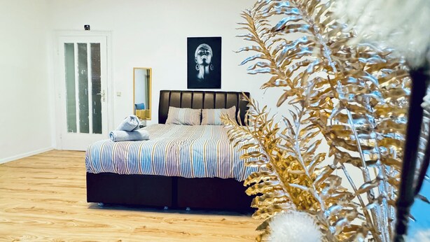 A bedroom with a bed, a mirror, a door, and a wall-mounted artwork. - Modern Studio for 3 Near FAC Platz (Wien)