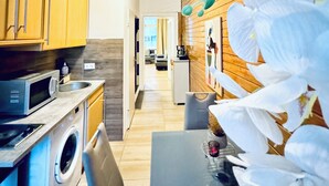 A modern kitchen with wooden cabinets, a microwave, and a washing machine. - Modern Studio for 3 Near FAC Platz (Wien)