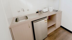 A kitchenette with a stainless steel sink, a toaster, a kettle, and a refrigerator. - Canberra Park Motel (Watson)