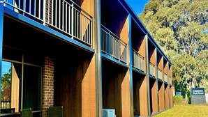 A multi-story hotel with balconies, outdoor seating, and a sign for the Canberra Park Motel. - Canberra Park Motel (Watson)