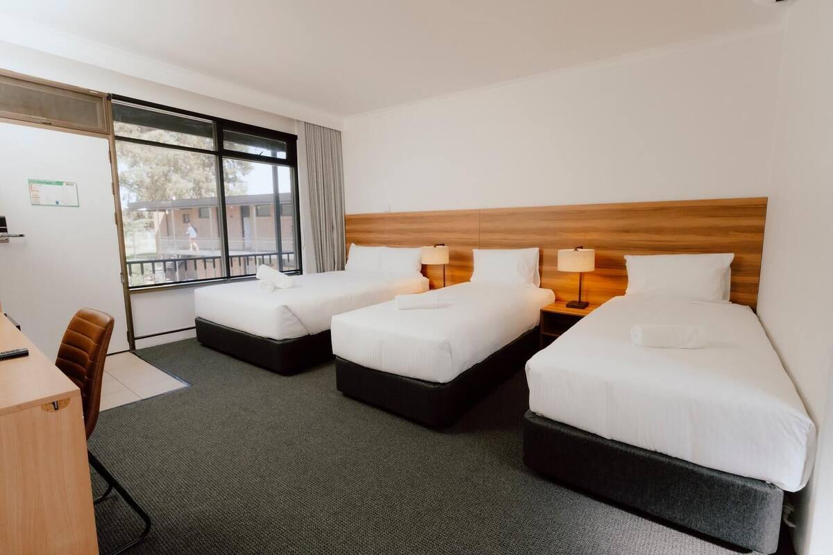 Une chambre d’hôtel avec deux lits, un bureau et une fenêtre donnant sur des immeubles.