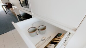 A white drawer with two mugs, a spoon, and a knife. - Canberra Park Motel (Watson)