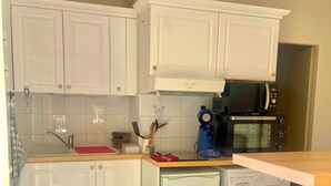 A kitchen with white cabinets, a microwave, a refrigerator, and a sink.