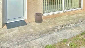 A building with a white door, a large sliding glass door, and a small trash can.