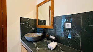 A bathroom with a large basin, a wooden-framed mirror, a towel, and a soap dispenser. - Villa Uma Asri (Ubud)