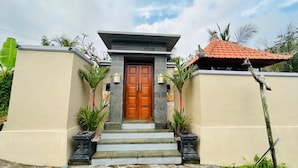 A building with a wooden door, stone steps, and a tiled roof. - Villa Uma Asri (Ubud)