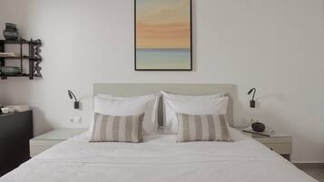 A neatly made bed with two pillows, a bedside table with a lamp, and a wall-mounted picture.