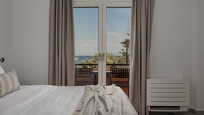 A bedroom with a bed, a window with curtains, a view of the outdoors, and a radiator.