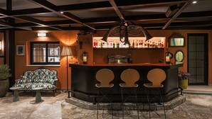 A bar area with a counter, stools, a sofa, and a window.