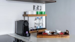 Une petite cuisine équipée d’une machine à café, de bouteilles d’eau et d’un plateau avec une tasse et des biscuits secs.
