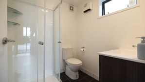 A bathroom with a glass shower enclosure, a toilet, a sink with a soap dispenser, and a window. - Queenstown Hill House - Studio Only. Lakeview Room, with a prime location and kitchen. (Queenstown)