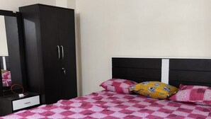 A bedroom with a bed, a wardrobe, and a nightstand. - Arjun Guest House (Bidhannagar)
