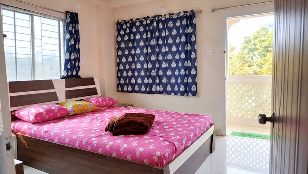 A bedroom with a bed, a window, a door, and a view of the outside. - Arjun Guest House (Bidhannagar)