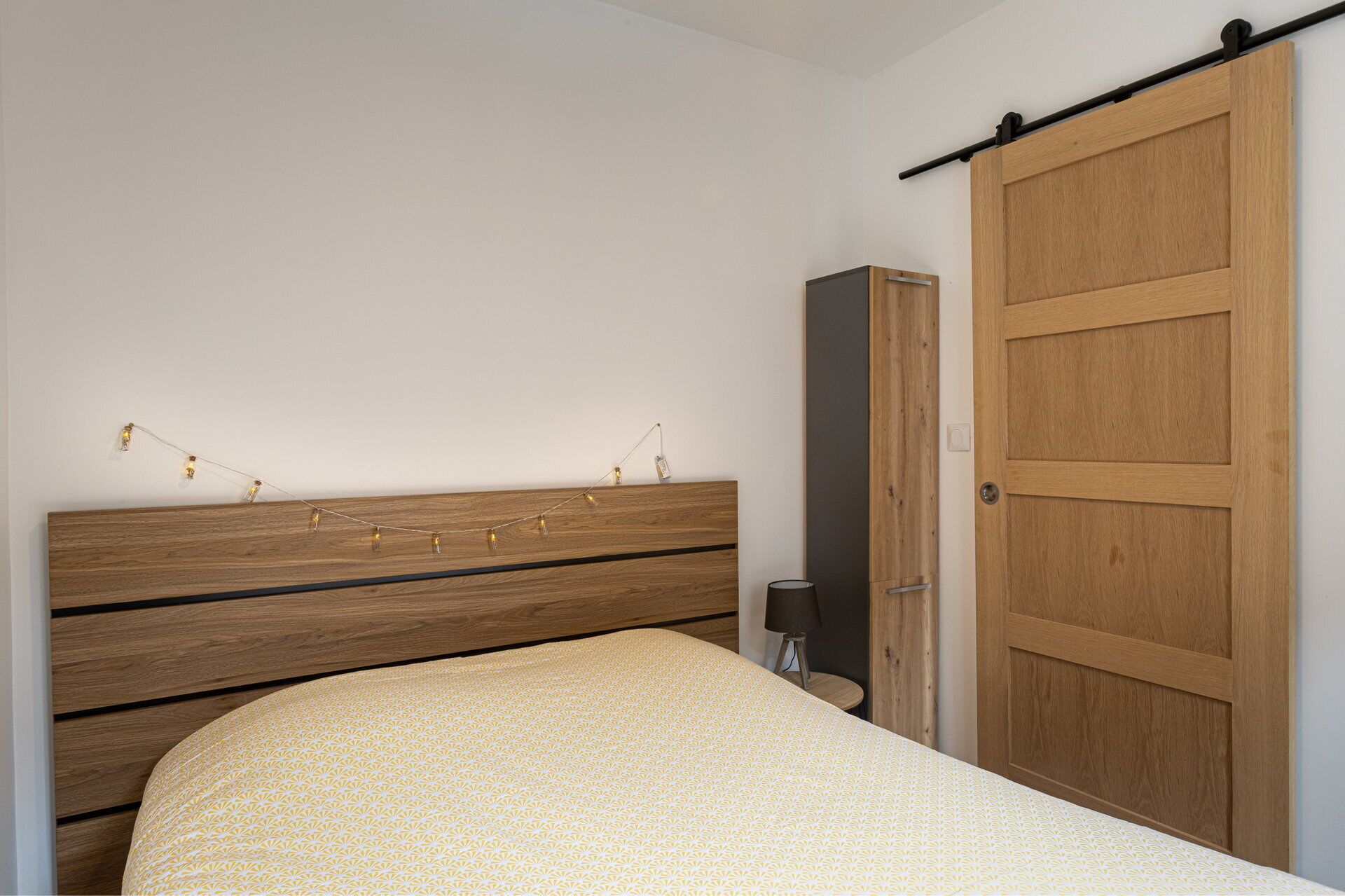 Ein Schlafzimmer mit einem hölzernen Bett, einem Kleiderschrank und einer Schiebetür.