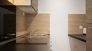 Una cocina moderna con encimera negra, electrodomésticos de acero inoxidable y muebles de madera.