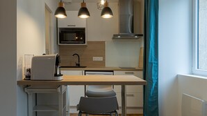 Et kompakt køkken med mikroovn, komfur og moderne hængelamper.