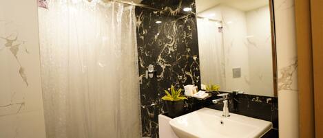 A bathroom with a marble wall, a shower curtain, a sink, and a mirror.