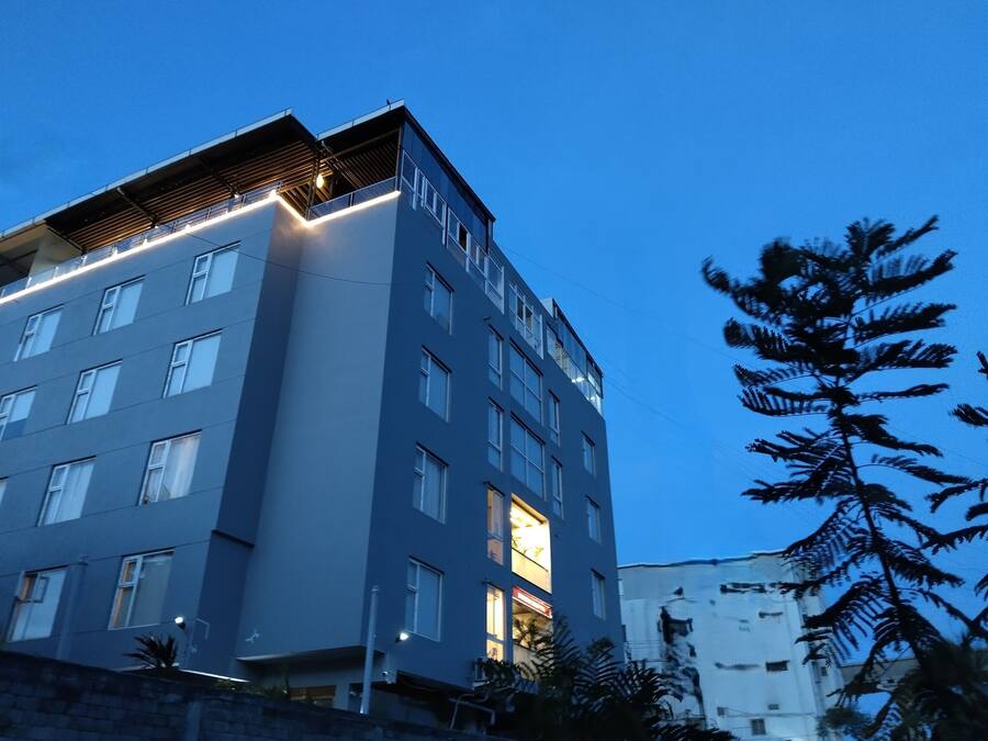 Un edificio de varios pisos con fachada plana, amplias ventanas y un balcón visible en los pisos superiores.
