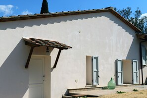 Un bâtiment avec un toit en tuiles, une porte et deux fenêtres équipées de volets.