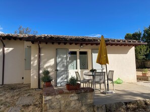 Un bâtiment avec un toit en tuiles, un mur en pierre et une terrasse avec des chaises et une table.