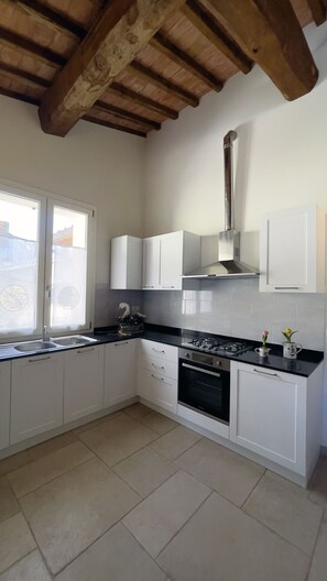 A kitchen with white cabinets, a black countertop, a stove, and a chimney. - Tuscan Villa Sport Relax (Colle di Val d'Elsa)