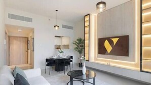 Una sala moderna con un sofá, una mesa de comedor y un televisor instalado en la pared.