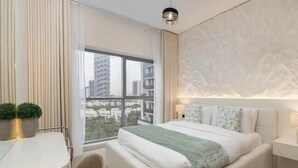 Un dormitorio moderno con un ventanal grande, una cama, una mesita y una silla.
