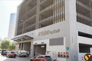 A building with a sign reading 'JEWEL by Badr' and a parking lot with several cars. - Vogue | Jeewar By Badr JVC near Circle Mall (Dubai)