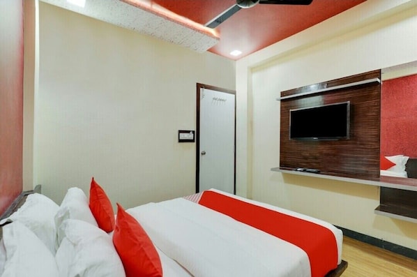 Habitación de hotel con cama, televisor montado en la pared y una puerta con un cartel.