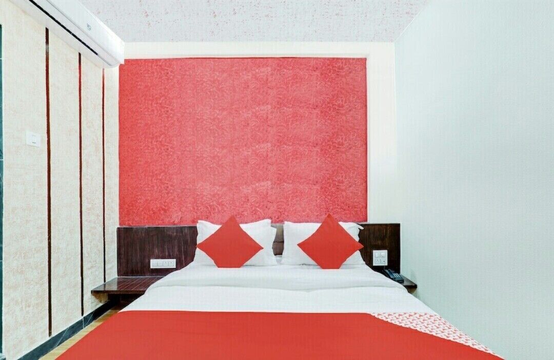 Ein Hotelzimmer mit einem Bett, einer roten Akzentwand, einem hölzernen Kopfteil und einem Nachttisch.
