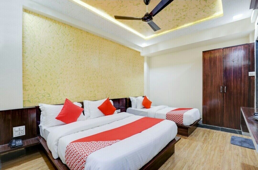 Ein Hotelzimmer mit zwei Betten, einem Deckenventilator, einem Kleiderschrank und einem Schreibtisch.