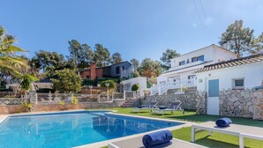 Una piscina con sillas de descanso y un muro de piedra.