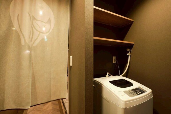 A laundry room with a washing machine, a towel rack, and a shower.