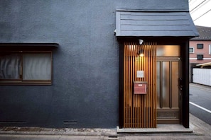 A building with a dark facade, a wooden door, and a small window. - Meguro Honcho (Tokyo)