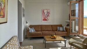 Un soggiorno con un divano marrone, una panca decorata, un tavolino da caffè con della frutta e una finestra con vista.