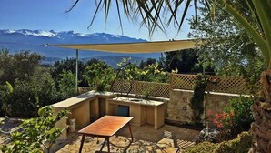 Un patio con tavolo e sedie, un muro in pietra e vista sulle montagne.