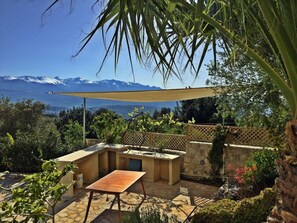 Eine Terrasse mit Tisch und Stühlen, eine Steinmauer und Blick auf Berge.