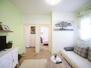 A living room with a sofa, a coffee table with a remote, a TV on a cabinet, and a painting on the wall. - Wohnung "Rustica mit exklusiver Nutzung des Pool by Interhome (Zadar)