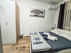 Ein Hotelzimmer mit zwei Betten, einem Wandbild, einer Klimaanlage und einem Fenster mit Vorhängen.
