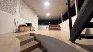 Una escalera conduce a una habitación con un banco de madera, una mesita y una pared con textura.
