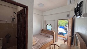 A compact room with a bed, a small table, a shower, and a window. - D 6 Apartment 6 of 6 (Ko Pha-ngan)
