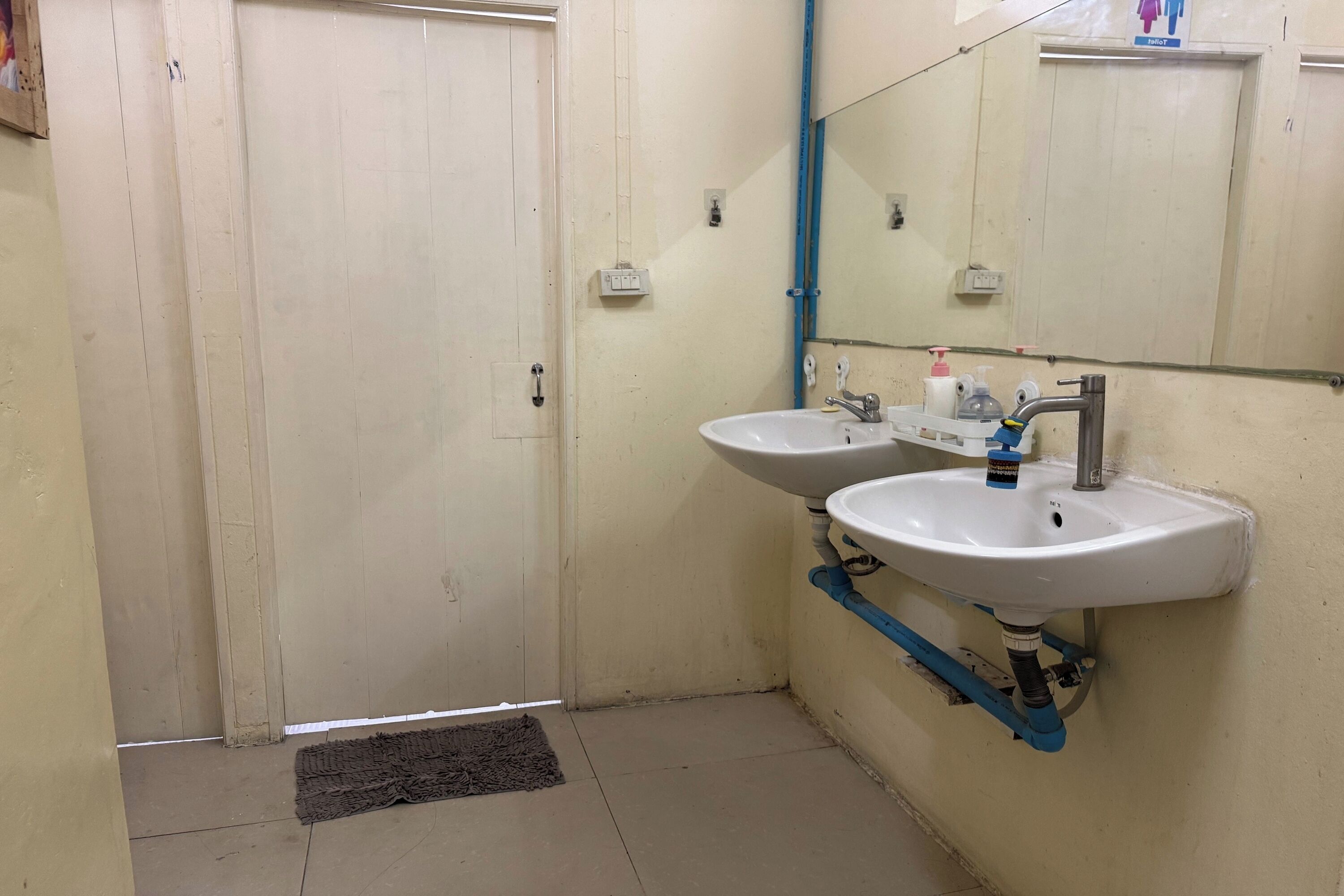 A bathroom with two sinks, a mirror, and a door.