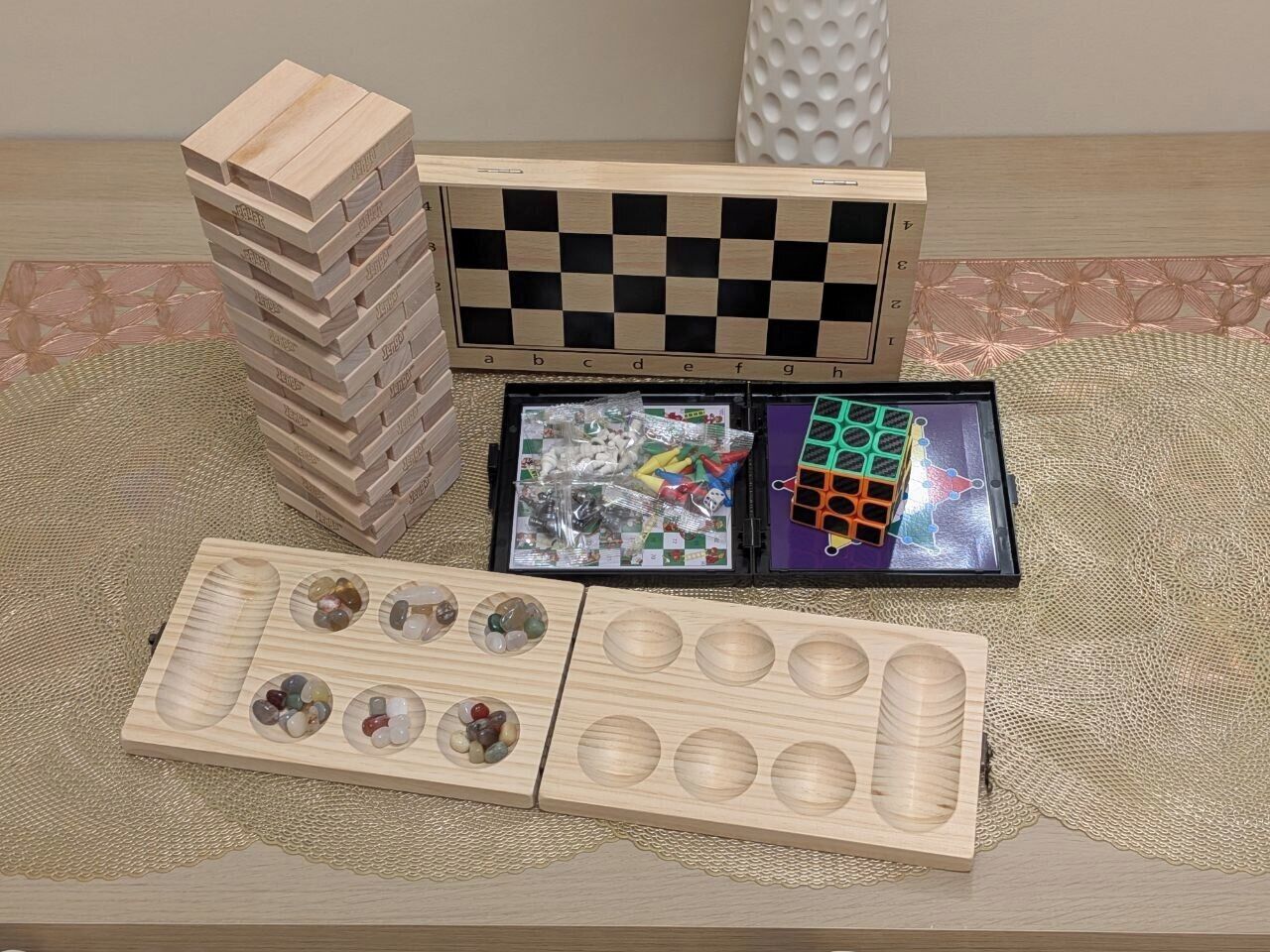 A wooden board game, a checkered board, and a Rubik's Cube on a table.