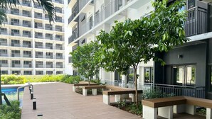 Un espace extérieur moderne doté d’une terrasse en bois, de bancs et d’une piscine.