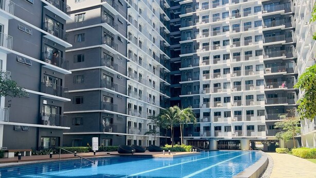 Un immeuble résidentiel moderne doté d’une piscine, de balcons et d’un jardin bien entretenu.